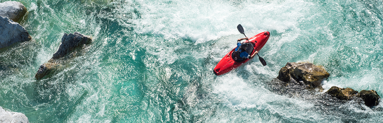 Mature man kayaking on river Soca rapids